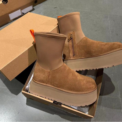 Brown suede platform boots with orange tag on a gray floor.