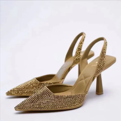 Gold studded high-heeled shoes on a white background