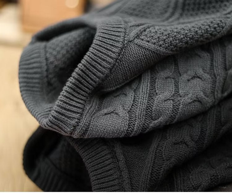 Stack of folded gray and black sweaters on a neutral background