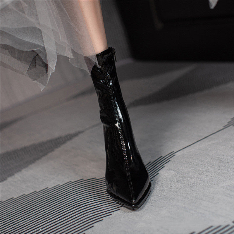 Black glossy high-heeled boot on a neutral background