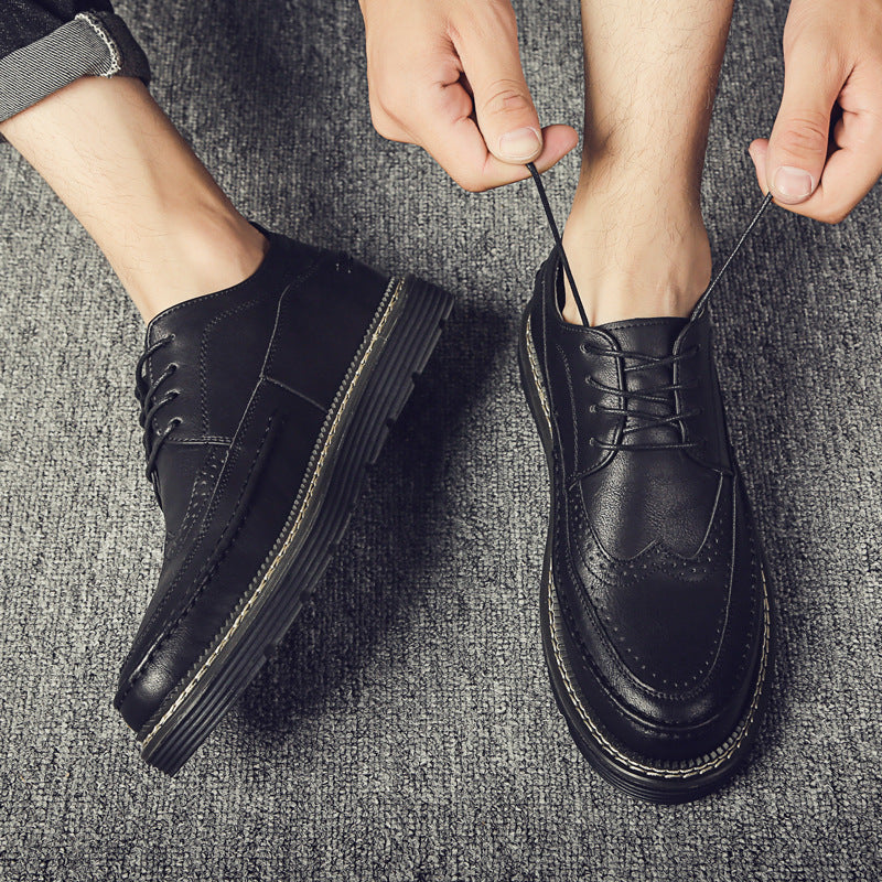 Person wearing black leather shoes on a textured gray surface