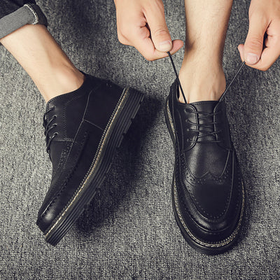 Person wearing black leather shoes on a textured gray surface
