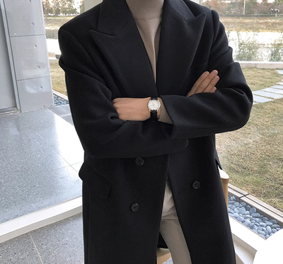 Person wearing a black coat with arms crossed, standing indoors.