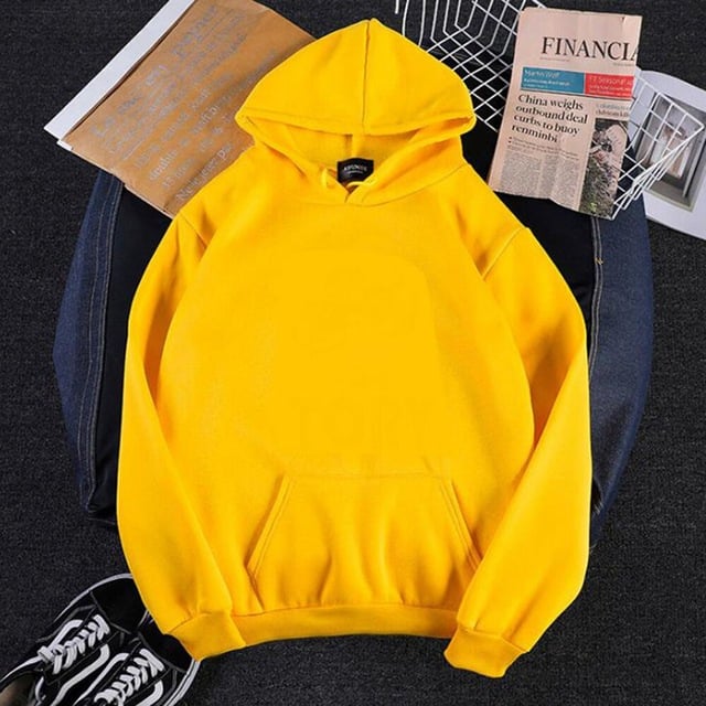 Yellow hoodie on a dark surface with a newspaper and sneakers