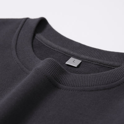 Close-up of a dark gray sweatshirt with a label on a light gray background