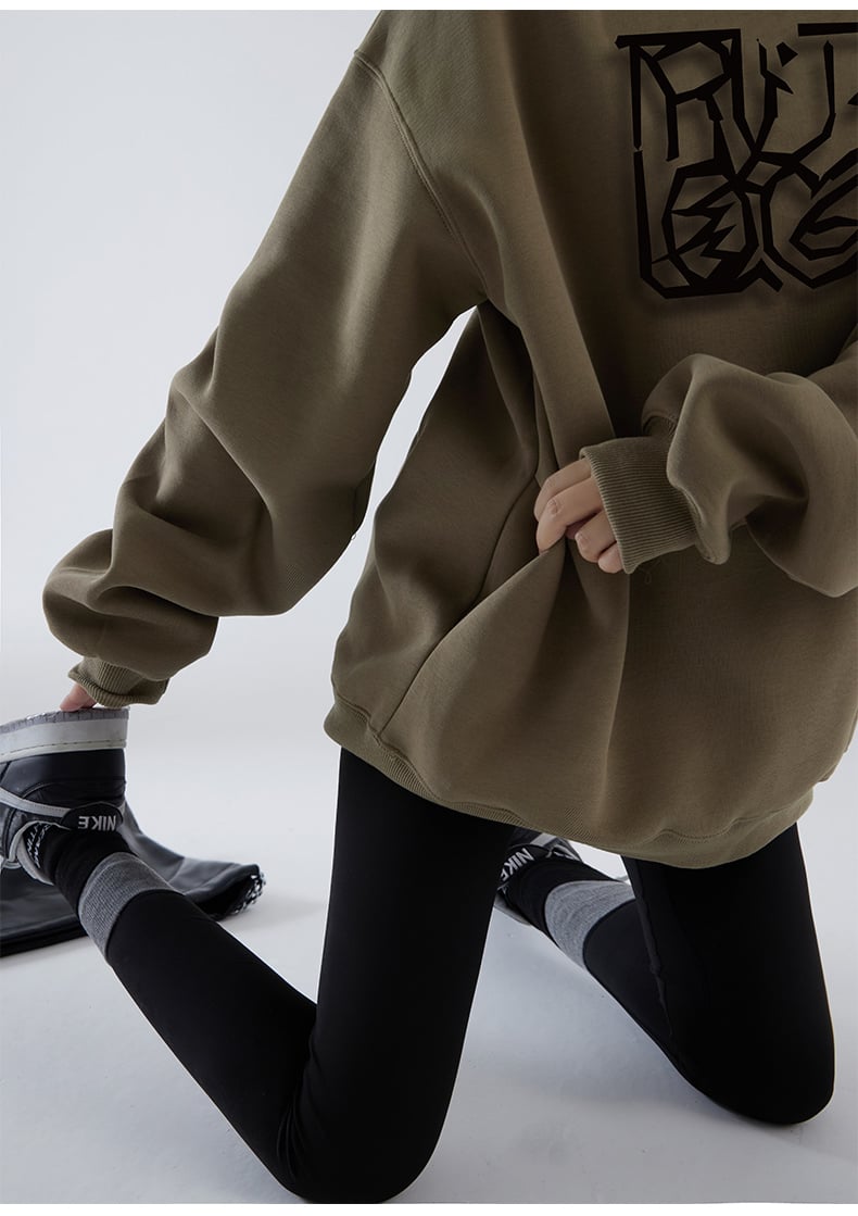 Person wearing a brown oversized hoodie with a black graphic design on a white background