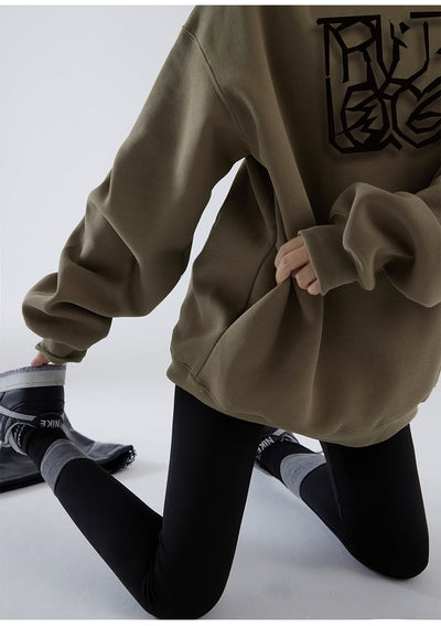 Person wearing a brown oversized hoodie with a black graphic design on a white background