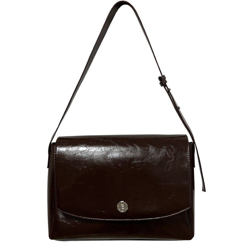 Brown leather handbag with a strap on a white background