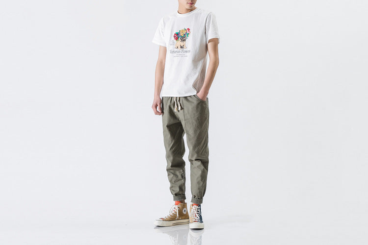Person wearing a white t-shirt with colorful graphics and green pants on a white background
