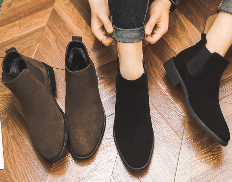 Brown and black ankle boots on a wooden floor with a person wearing them.