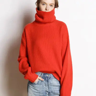 Person wearing a red turtleneck sweater and blue jeans against a plain background