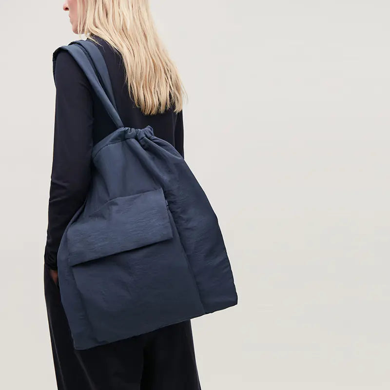 Person wearing a navy blue backpack against a plain background