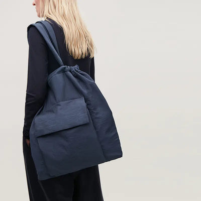 Person wearing a navy blue backpack against a plain background