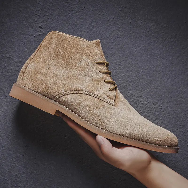 Beige suede shoe held by a hand against a dark background