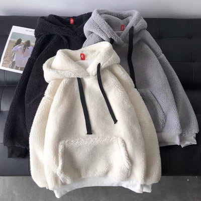 Three fleece hoodies in black, white, and gray on a dark surface.