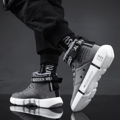 Gray high-top sneakers with white soles on a reflective surface and dark background