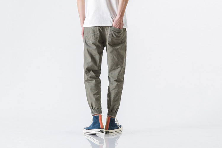 Person wearing olive green jogger pants and multicolored sneakers on a white background