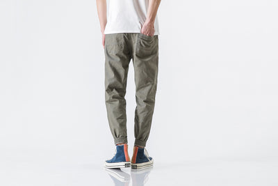 Person wearing olive green jogger pants and multicolored sneakers on a white background