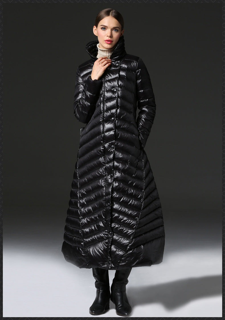 Woman wearing a long black puffer coat against a gray background