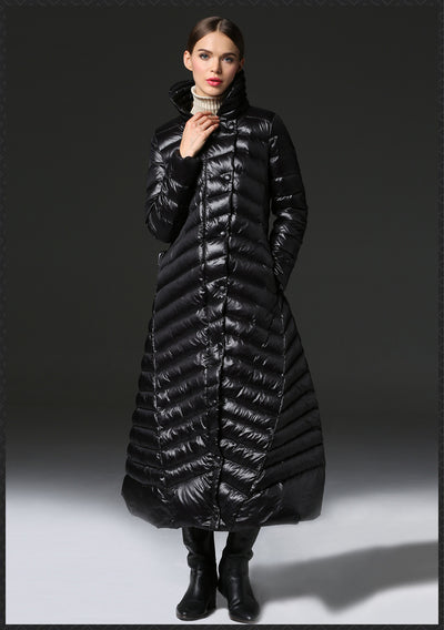 Woman wearing a long black puffer coat against a gray background