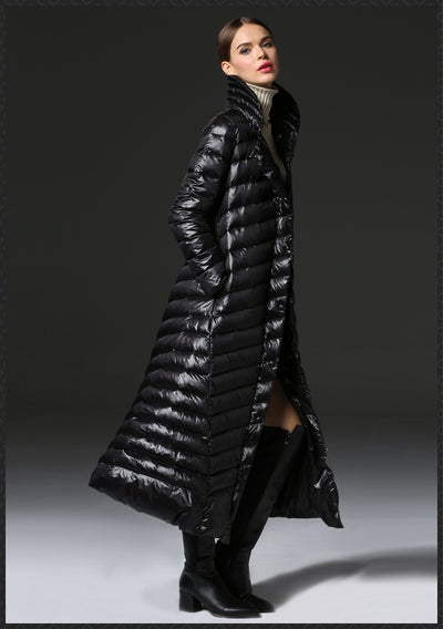 Woman wearing a long black puffer coat on a gray background