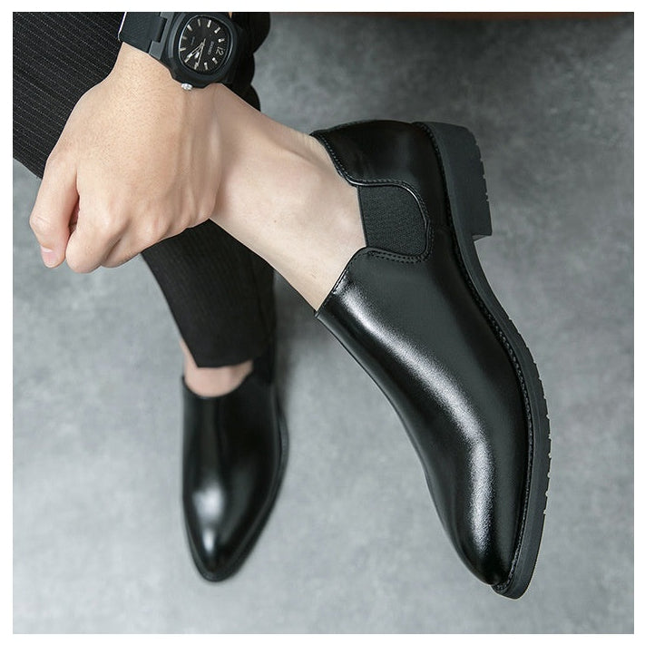 Black leather shoes worn by a person on a gray background