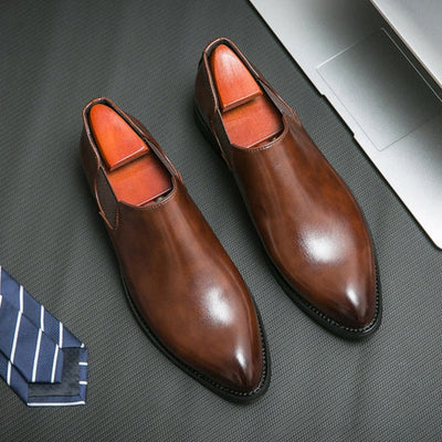 Brown dress shoes with orange lining on a textured surface with a tie.