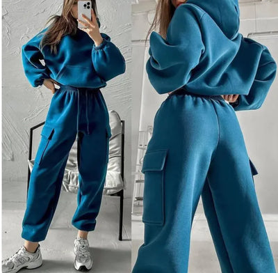 Person wearing a blue tracksuit in a room with a chair and pillow in the background.