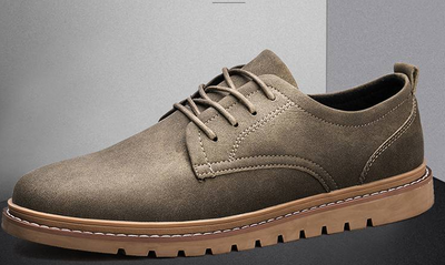 Brown suede shoe with a brown sole on a gray background