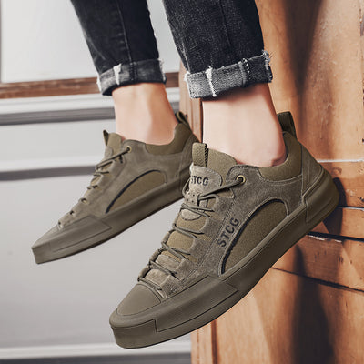 Green sneakers with 'STCG' branding worn by a person on a wooden floor.