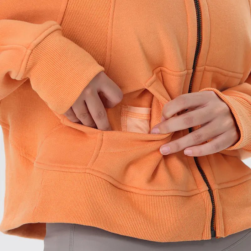 Person wearing an orange jacket with a close-up of the zipper and pocket area.