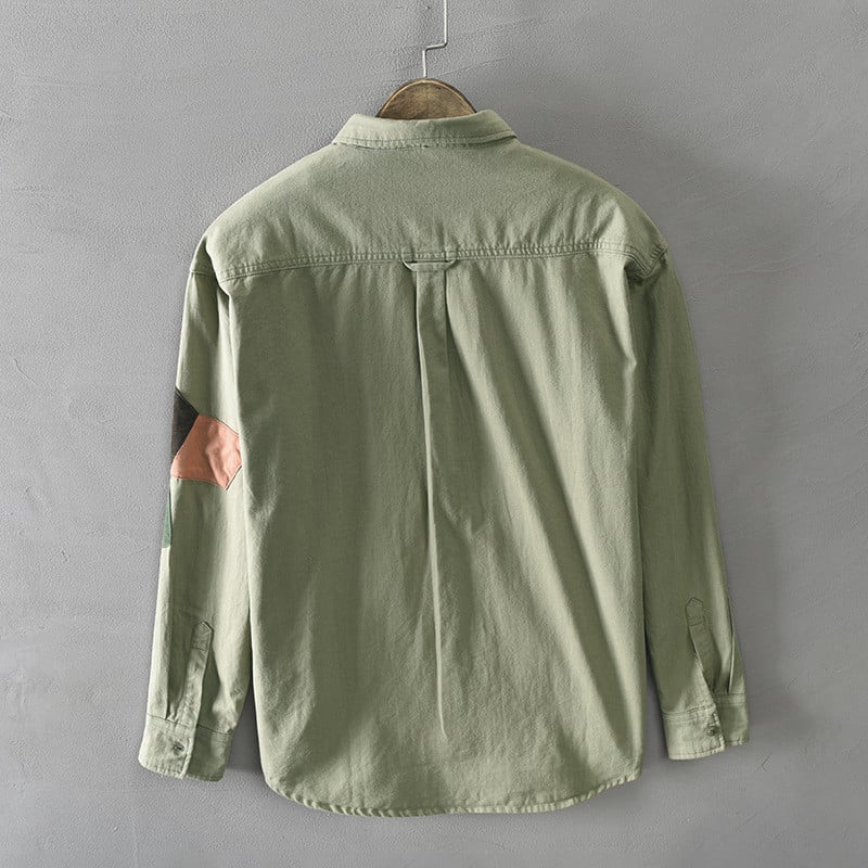 Green shirt on a hanger against a gray background