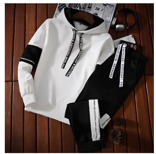 White and black hoodie with text on sleeves and pants on a wooden surface