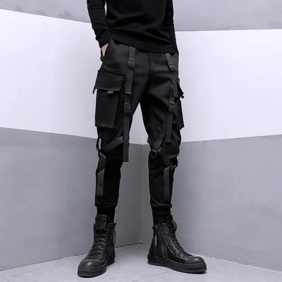 Person wearing black cargo pants and black boots against a gray and white background