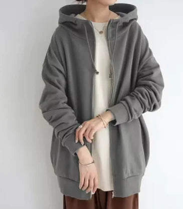 Person wearing a long gray hoodie over a white shirt on a plain background