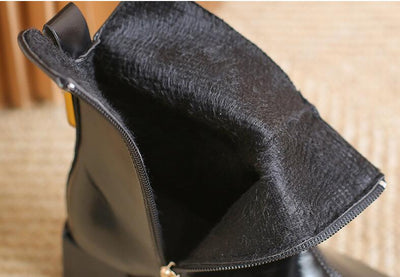 Close-up of a black leather bag with a textured surface on a wooden floor.