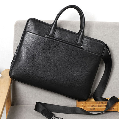 Black leather briefcase on a gray surface with a wooden box in the background
