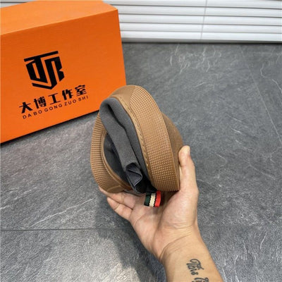 Hand holding a brown belt with a gray interior, in front of an orange box with black text.
