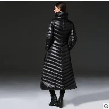 Person wearing a long black puffer coat on a dark background