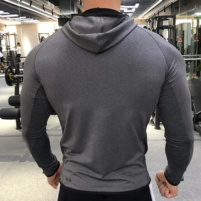 Person wearing a gray hoodie in a gym setting