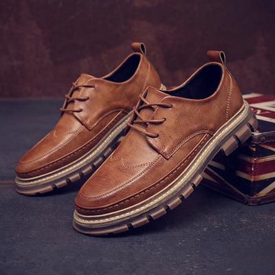 Pair of brown leather shoes on a dark surface with a blurred background