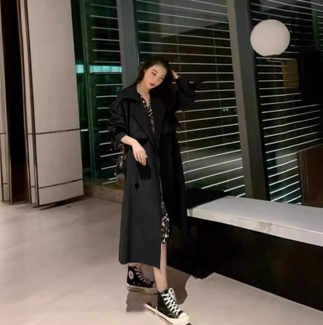 Person wearing a black coat and high-top sneakers in an urban setting