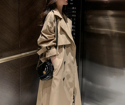 Person wearing a beige trench coat in an elevator