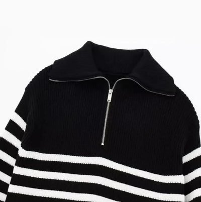 Black and white striped sweater with a zipper on a light gray background