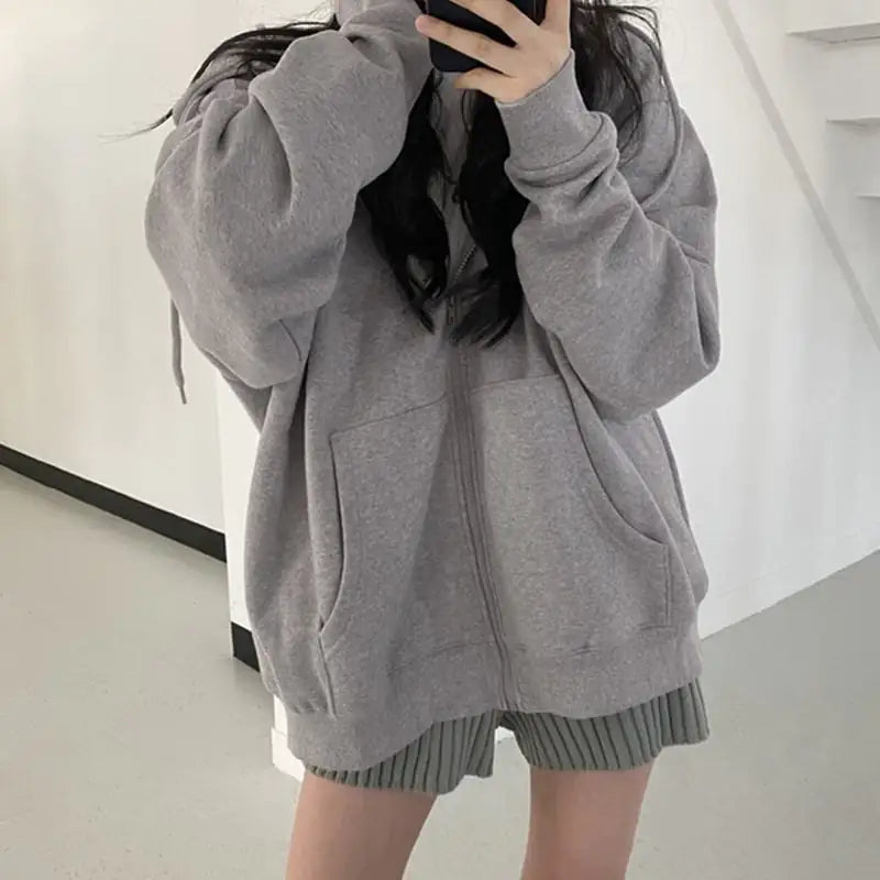 Person wearing a gray hoodie and shorts in a minimal indoor setting