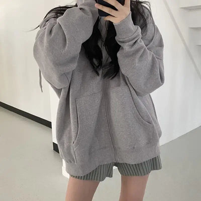 Person wearing a gray hoodie and shorts in a minimal indoor setting