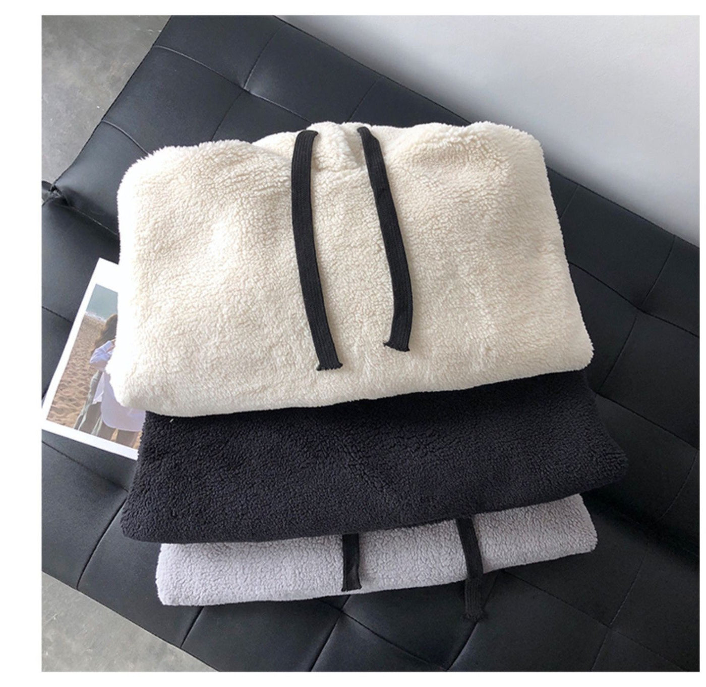 Stack of folded towels in white, black, and gray on a black leather surface.
