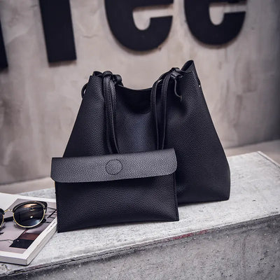 Two black leather handbags on a concrete surface with sunglasses and a magazine.
