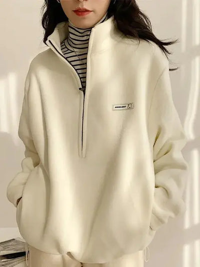 Person wearing a beige fleece jacket with a brand logo on a neutral background