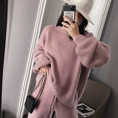 Person wearing a pink sweater and white hat taking a mirror selfie.